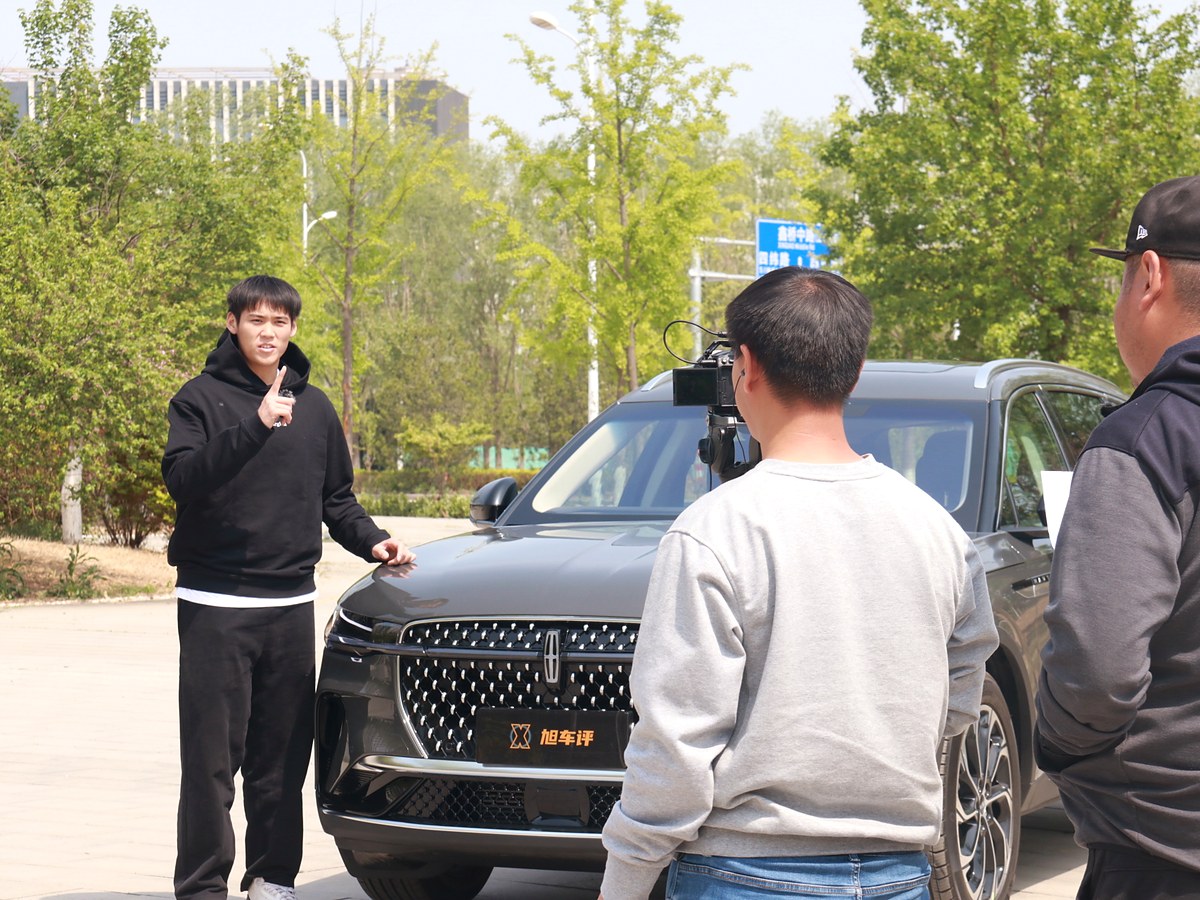 Adam Zhang delivering the on-camera voiceover beside the Lincoln Nautilus