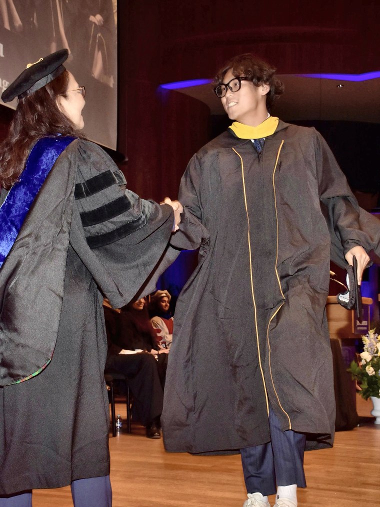 Adam Zhang shaking hands with the dean at his Johns Hopkins Carey commencement