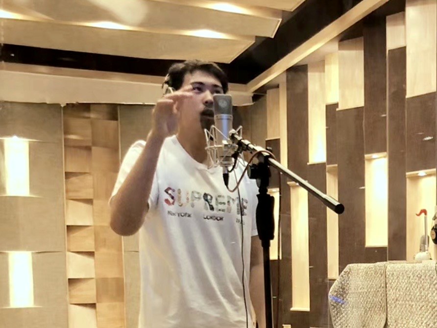 Adam Zhang recording vocals at a studio microphone