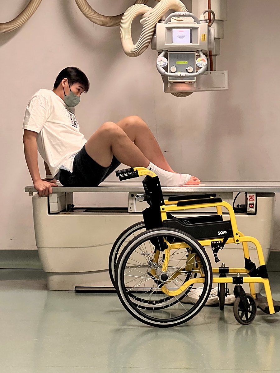 Adam Zhang in a wheelchair with a bandaged foot in the X-ray room